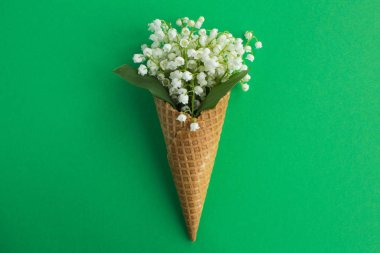 Yeşil arka plan merkezinde vadinin zambaklar ile dondurma konisi. Üst te. Kopya alanı. Bahar çiçekleri kavramı.