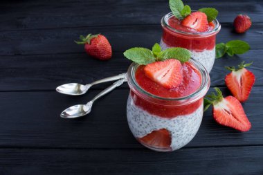 Siyah ahşap arka plan üzerinde chia ve çilek ile Puding