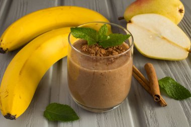 Gri ahşap arka plan üzerinde muz, armut ve kakao ile Smoothie