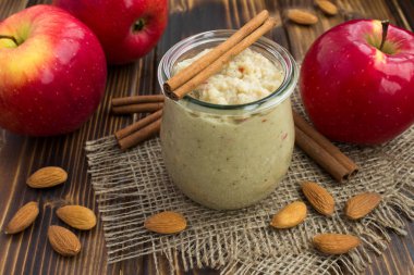 Rustik ahşap arka plan üzerinde kırmızı elma, badem ve tarçın smoothies