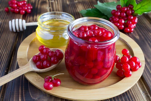 Yuvarlak ahşap kesme tahtası üzerinde bal ile Viburnum reçel