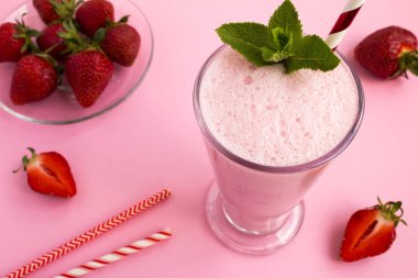 Pembe arka plan üzerinde cam çilek milkshake. Üstte görüntü.