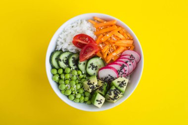 Sarı arka plan ortasında beyaz kase beyaz pirinç ve sebze ile Vegan poke kase. Üst te. Closeup.