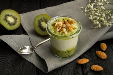 Siyah ahşap arka plan üzerinde kivi ve fındık ile Süt yoğurt