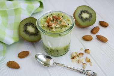 Beyaz ahşap arka plan üzerinde kivi ve fındık ile Süt yoğurt