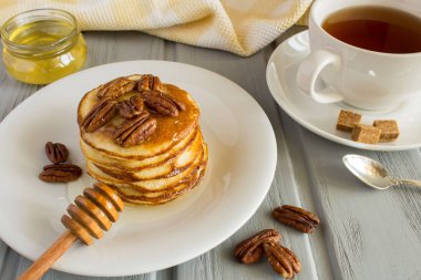 Gri ahşap arka plan üzerinde beyaz tabakta ceviz ve bal ile krep