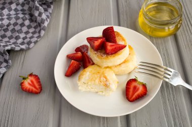 Gri ahşap arka planda peynirli krep, çilek ve bal