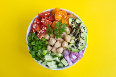 Sarı arka plan ortasında beyaz kase nohut ve sebze ile Vegan poke kase. Üst te. Closeup.
