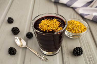 Gri ahşap arka plan üzerinde böğürtlen ve arı poleni ile Smoothies