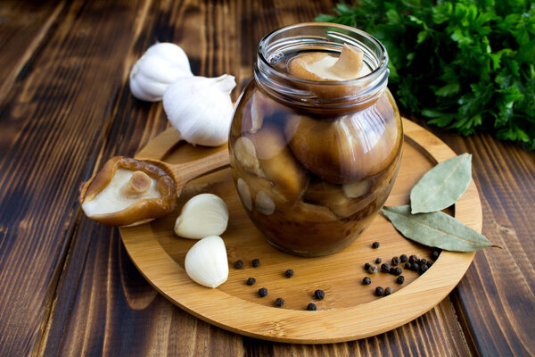 Marinated mushrooms shiitake in the glass jar on the brown wooden background