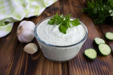 Kahverengi ahşap arka planda salatalık ile geleneksel Yunan yoğurt. Closeup.