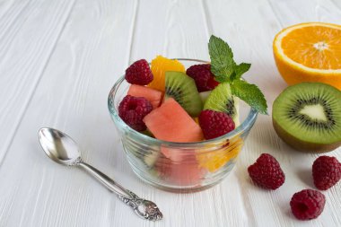 Beyaz ahşap arka planda küçük cam kase meyve salatası. Closeup.
