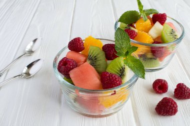 Beyaz ahşap arka planda meyve salatası ile iki cam küçük kase