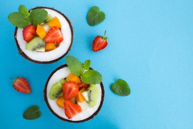 Mavi arka planda yarım hindistan cevizi meyve salatası. Üst te. Kopyalama alanı.