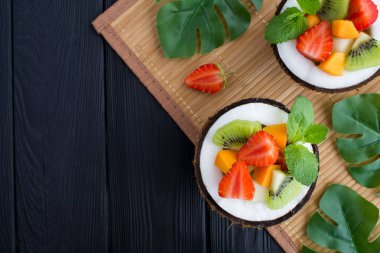 Tropikal arka planda yarım hindistan cevizi meyve salatası. Üst te. Kopyalama alanı.