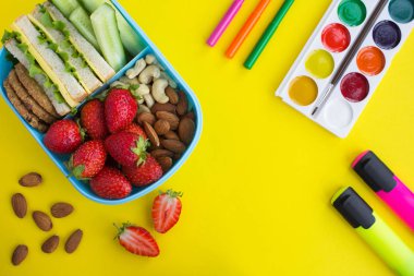 Mavi kutuda okul öğle yemeği ve sarı arka planda okul kırtasiye. Üst te. Kopyalama alanı.