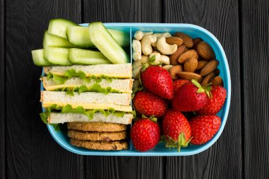 Siyah ahşap arka plan merkezinde mavi kutuda Öğle yemeği. Üstte görüntü.