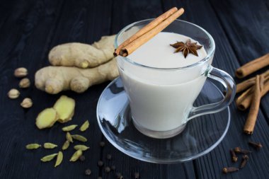 Cam bardak çay masala ve siyah ahşap arka plan üzerinde malzemeler. Closeup.