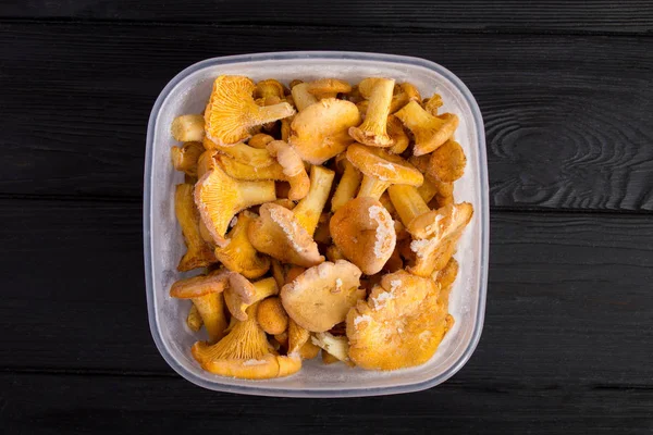 Siyah ahşap arka plan merkezinde kutusunda Dondurulmuş chanterelle mantar. Üst te. Kopya alanı. Sağlıklı gıda.