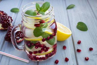 Hafif ahşap arka planda nar, limon ve nane ile detoks suyu