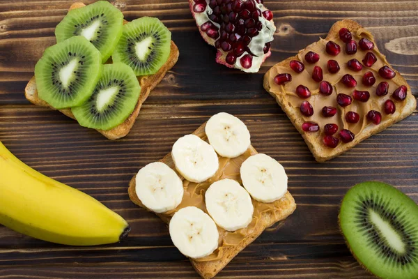 Toasts  with peanut paste and fruit on the wooden background