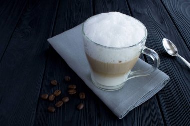 Siyah ahşap arka plan üzerinde cam fincan kahve latte. Closeup. Kopyalama alanı.