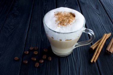 Siyah ahşap arka plan üzerinde cam fincan tarçın ile Kahve latte. Closeup. Kopyalama alanı.