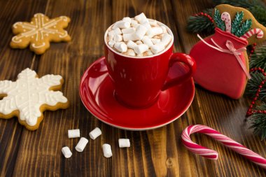 Kırmızı fincan marshmallow si ile sıcak çikolata ve kahverengi ahşap arka plan üzerinde Noel gingerbreads