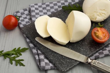Gri kesme tahtası üzerinde dilimlenmiş mozzarella