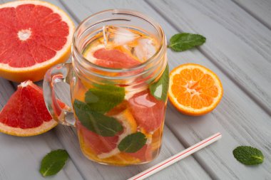 Gri ahşap arka plan üzerinde mandalina ve greyfurt ile detoks suyu