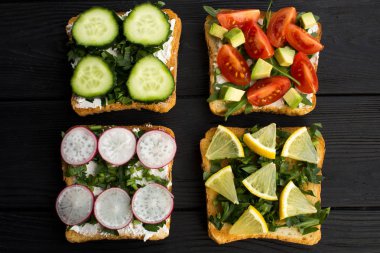 Siyah ahşap arka plan üzerinde sebze ve meyve ile Vejetaryen sandviçler. Üstte görüntü.