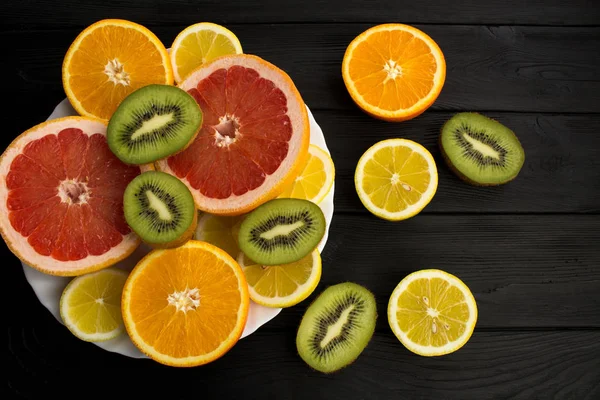 Frutta Tropicale Affettata Sul Piatto Bianco Sullo Sfondo Legno Nero — Foto Stock