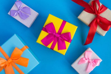 Mavi arka planda parlak fiyonklu çok renkli hediye kutuları. Üstte görüntü.