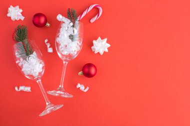 Kırmızı arka planda iki kadeh şampanyayla Noel kompozisyonu. Kopya alanı. Üstte görüntü.