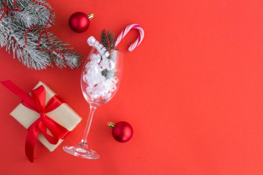 Bir şampanya bardağı ve kırmızı arka plan üzerinde hediye ile Noel kompozisyon. Kopya alanı. Üstte görüntü.