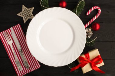 Siyah ahşap arka plan üzerinde boş beyaz plaka ve Noel kompozisyon. Üst te. Kopyalama alanı.