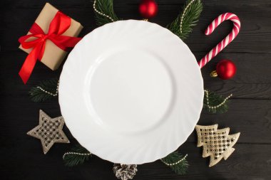 Siyah ahşap arka plan üzerinde boş beyaz plaka ve Noel kompozisyon. Üst te. Kopyalama alanı.