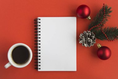 Açık not defteri, beyaz fincanda sade kahve ve kırmızı arka planda Noel kompozisyonu. Uzayı kopyala Üst görünüm.
