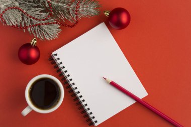 Açık not defteri, beyaz fincanda sade kahve ve kırmızı arka planda Noel kompozisyonu. Uzayı kopyala Üst görünüm.