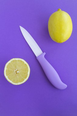 Violet knife  and lemon on the violet background. Top view. Copy space. Location vertical. clipart