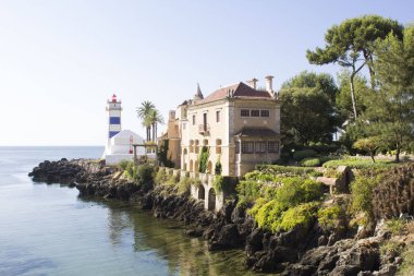 Güneşli bir günde güzel bir sahil manzarası, deniz feneri ve villa. Cascais. Portekiz.