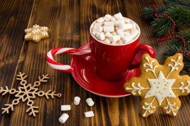 Kırmızı fincan marshmallow si ile sıcak çikolata ve kahverengi ahşap arka plan üzerinde Noel gingerbreads