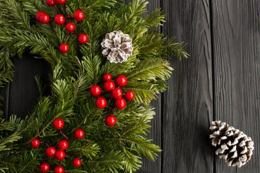 Noel kompozisyonu. Siyah ahşap arka planda Noel yüzüğü ya da çelenk. Üst Manzara. Boşluğu kopyala.