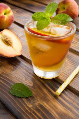 Kahverengi ahşap arka planda şeftalili soğuk çay. Konum dikey.