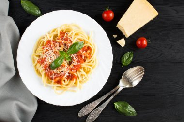 Domates soslu İtalyan makarnası ve siyah ahşap kaplamalı beyaz tabakta parmesan. Üst Manzara. Boşluğu kopyala.