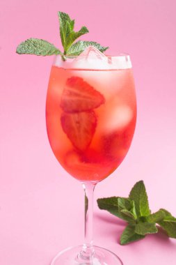 Pembe arka planda çilekli ve buzlu kokteyl. Konum dikey. Yakın çekim..