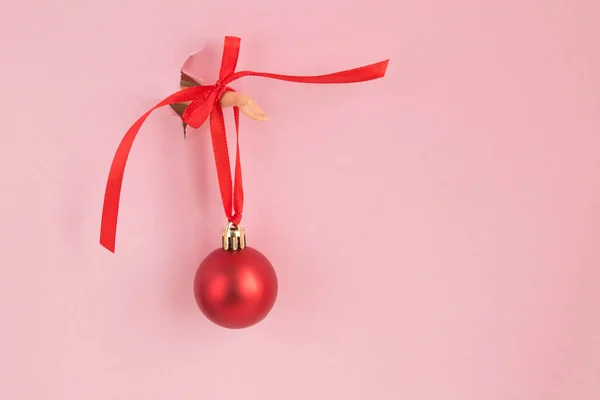 Női Kéz Egy Piros Karácsonyi Labdával Amit Egy Lyukas Rózsaszín — Stock Fotó
