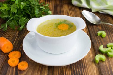 Kahverengi ahşap arka plandaki beyaz kasede tavuk suyu çorbası. Yakın çekim..