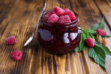 Kahverengi ahşap yüzeydeki cam kavanozda ahududu reçeli. Yakın çekim..