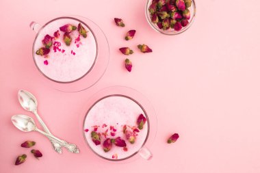 Pembe yüzeyde iki kapta gül ay sütü manzarası. Boşluğu kopyala.